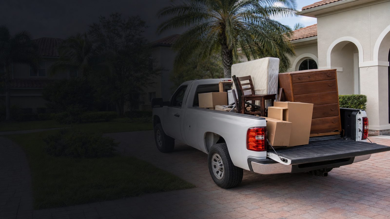 Pickup truck loaded with a mattress, dresser and boxes outside a Florida home